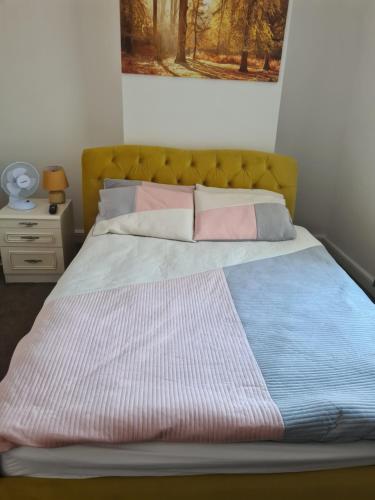 a bed with a yellow headboard and pillows on it at Carfax House in Manchester