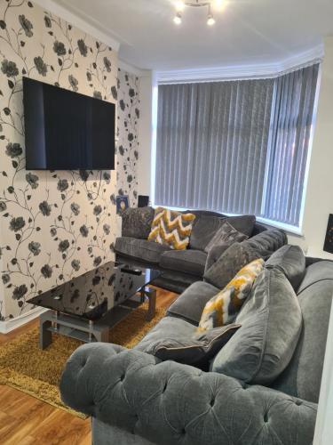 a living room with a couch and a flat screen tv at Carfax House in Manchester