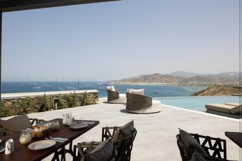 a patio with a table and chairs and a view of the ocean at Virtu on the Hill in Stelida