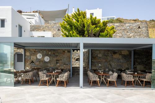 a restaurant with tables and chairs and a stone wall at Virtu on the Hill in Stelida