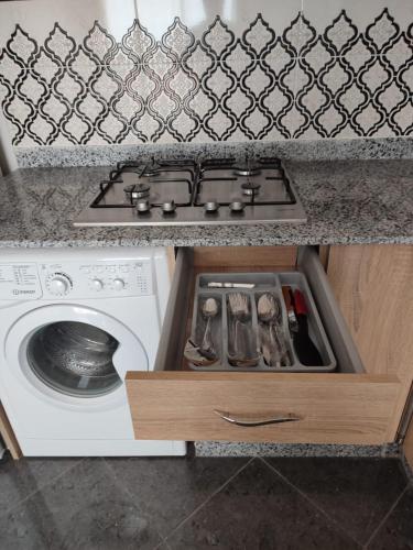 a kitchen counter with a stove and a washing machine at Résidence Les Deux Mules in Ahfir