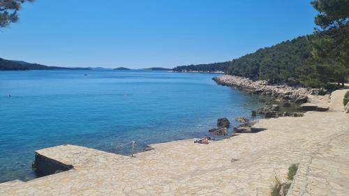 a beach with people sitting on the sand next to the water at Apartments Valentina Tisno in Tisno