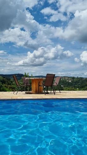 a swimming pool with two chairs and a table and a table and chairs at Chácara, próx a SP, com WI-FI e uma vista incrível in São Roque
