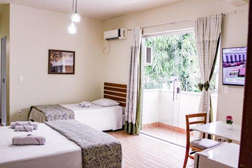 a hotel room with two beds and a balcony at Hotel Primavera Betim in Betim