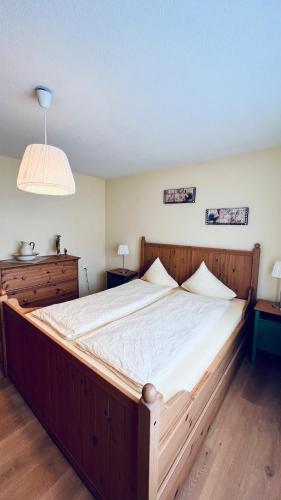 ein großes Holzbett in einem Zimmer mit 2 Tischen in der Unterkunft Casa Terza - CharmingStay in Flumserberg