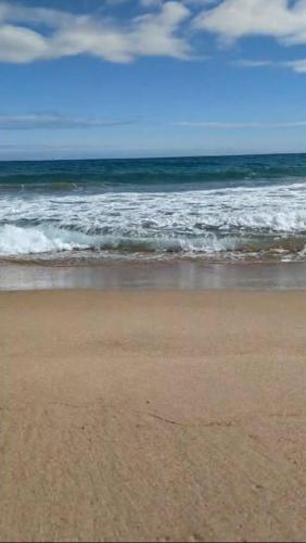 a sandy beach with waves in the ocean at Résidence Les Deux Mules in Ahfir