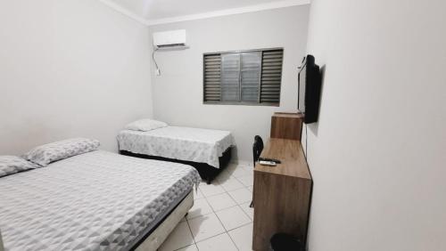 a small room with two beds and a window at Pousada São Francisco in Cuiabá