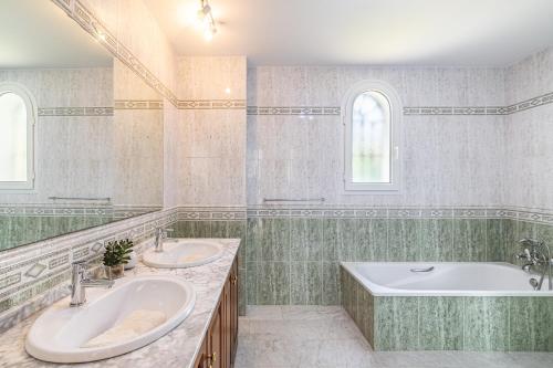 Un baño con dos lavabos y una bañera. en Villa Panorama, en Manilva