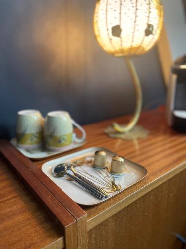 a table with a plate with silverware and a lamp at La Maison aux murs anciens et ses chambres in Tarbes