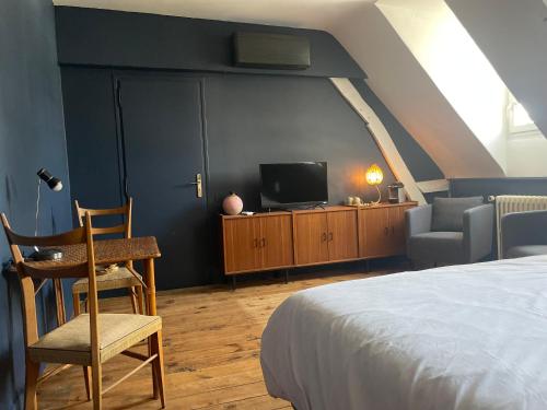a bedroom with a bed and a desk and a tv at La Maison aux murs anciens et ses chambres in Tarbes