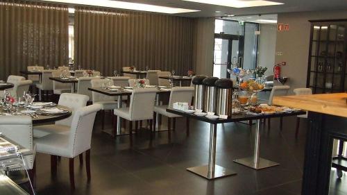 una sala da pranzo con sedie e tavoli bianchi in un ristorante di Casa do Adro Hotel a Ferreira do Zêzere