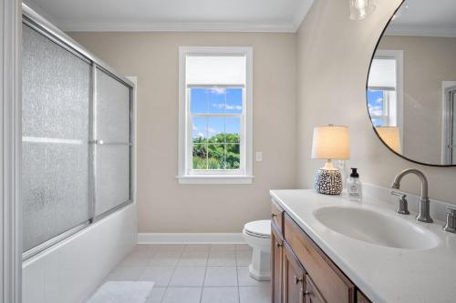 a white bathroom with a sink and a mirror at Lowcountry State of Mind luxury beach getaway located on Harbor Island, South Carolina in St. Helena Island