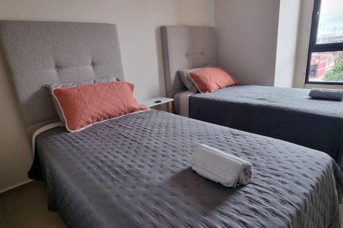 a room with two beds and a bag on the bed at Hermoso departamento cerca del Auditorio Telmex in Guadalajara