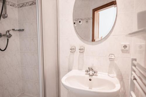 a white bathroom with a sink and a mirror at Hotel am Fluss in Heidesee