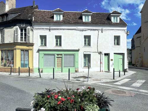 a white building with green doors on a street at Place Sainte Marguerite in Provins