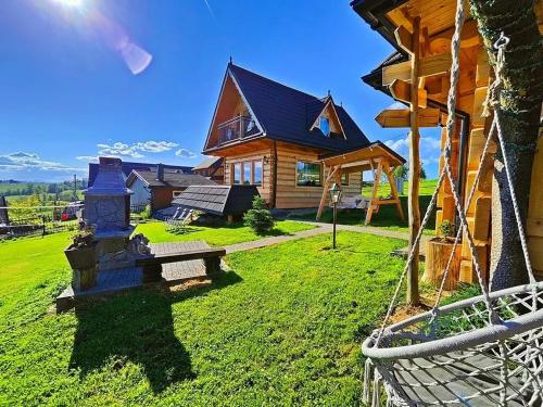 a log house with a swing in front of it at Domek u Śpiewoka 1 in Maruszyna