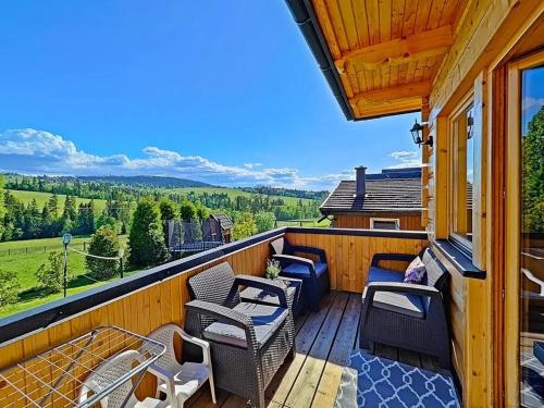 a balcony with chairs and tables and a view at Domek u Śpiewoka 1 in Maruszyna