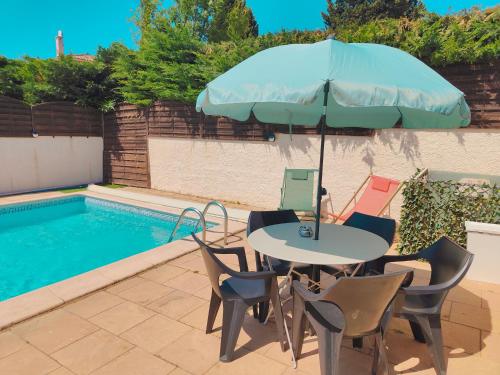 une table et des chaises avec un parasol à côté d'une piscine dans l'établissement Bel appartement avec piscine, à Martigues
