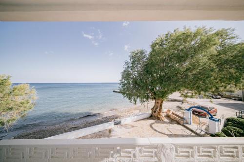 a view of a beach with a tree and the ocean at Fotis beach apartment at Komi in Kómi