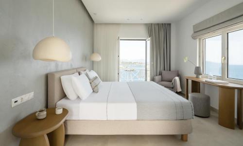 a bedroom with a bed and a desk and a window at Oniro Skiathos in Skiathos Town