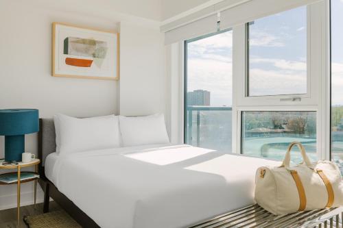uma cama branca num quarto com uma grande janela em Sonder at Artesa em Toronto