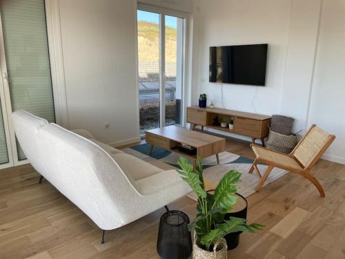 un salon avec un canapé blanc et une télévision dans l'établissement Appartement neuf centre station a 200m de la plage, à Neufchâtel-Hardelot