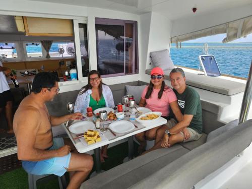 a group of people sitting around a table on a boat at Private Catamarán With Crew - DON C - Lagoon 40 feet - All Inclusive in Isla Wichitupo Grande