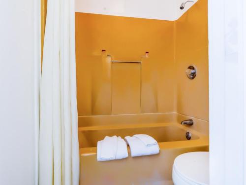 ein Badezimmer mit einer Badewanne, einem WC und Handtüchern in der Unterkunft Country Hearth Inn & Suites By OYO Sturgis in Sturgis