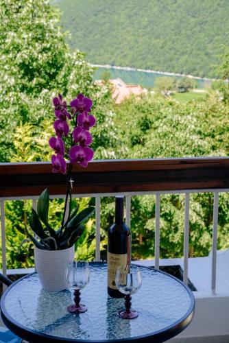 a table with a bottle of wine and a flower at Panorama Plužine Apartment in Pluzine