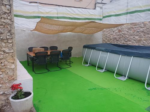 Habitación con mesa, sillas y suelo verde. en El Rincon De Luna en Moratilla de los Meleros