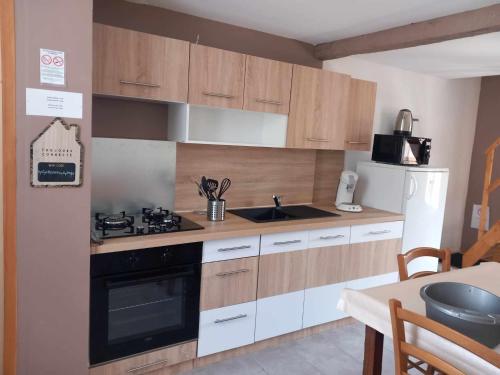 uma cozinha com armários de madeira, um fogão e um lavatório em gite the georgette house em Pontorson
