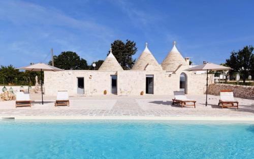 a house with a pool in front of a building at Trulli Fortunato private, heated swimming pool in Locorotondo