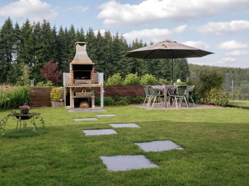 a backyard with an outdoor grill and an umbrella at Appartement Sur Jardin Verdoyant in Bertrix
