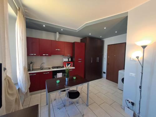 a kitchen with red cabinets and a table with chairs at Appartamento Valentina in Cremona