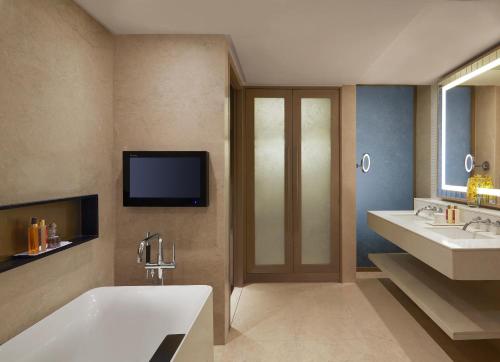 a bathroom with a tub and two sinks and a tv at Taj Santacruz in Mumbai