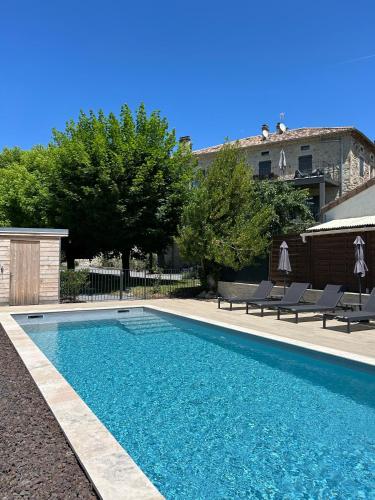 une piscine dans une cour avec des chaises et un bâtiment dans l'établissement Clos des Mouliniers - Gîtes 5 étoiles en Ardèche, à Saint-Privat