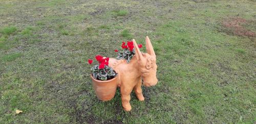 a cat statue holding a flower pot with red flowers at La roulotte des Trois Arbres in Oradour-sur-Glane