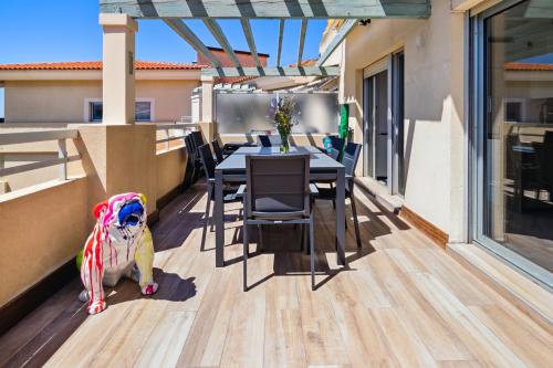 a dog sitting on a balcony with a table and chairs at DUPLEX VILLA LES PINS 89m2 et terrasse 30m2 in Antibes
