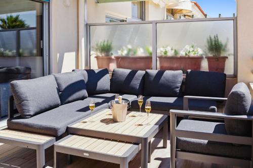 a couch on a patio with two tables and glasses of wine at DUPLEX VILLA LES PINS 89m2 et terrasse 30m2 in Antibes