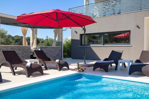 uma piscina com cadeiras e um guarda-sol vermelho ao lado de uma piscina em Villa Edis em Pula