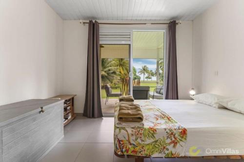 モーレア島にあるSeaside Paradise Retreat - 3BR House in Mooreaのベッドとガラスの引き戸のある寝室