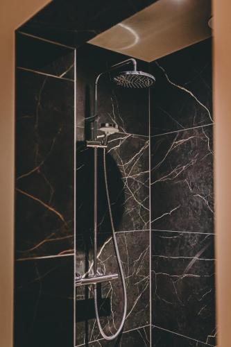 a shower in a bathroom with black marble at Hotel Centraal Baarlo in Baarlo