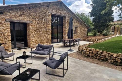 a patio with chairs and an umbrella in front of a building at L'Escale Nobilienne in Nouaillé-Maupertuis