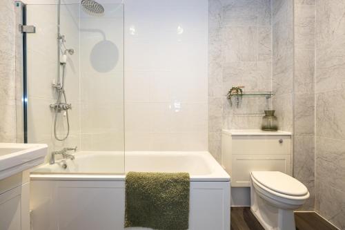 a bathroom with a tub and a toilet and a sink at Boutique City Centre Apartment in Manchester