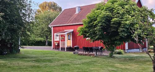a red barn with a table and chairs in front of it at Fully equipped house in the countryside at Knohult in Aneby