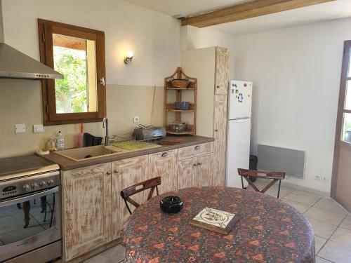 une cuisine avec une table et un réfrigérateur blanc dans l'établissement Villa vue sur la Garrigue avec piscine, à Valliguières