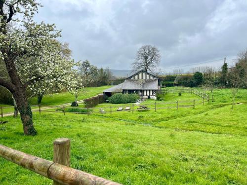 an old barn in a field with a fence at Paisible cottage au bord de l'eau -15 mn des côtes in Pierrefitte-en-Auge