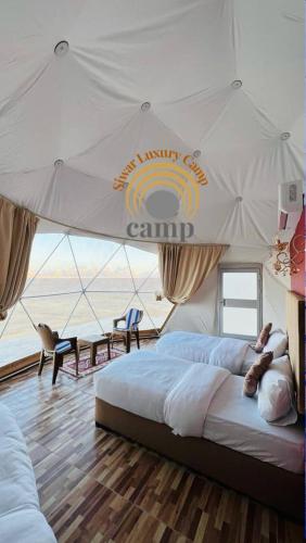 Siwar Luxury Camp في وادي رم: غرفة نوم بسريرين ومظلة