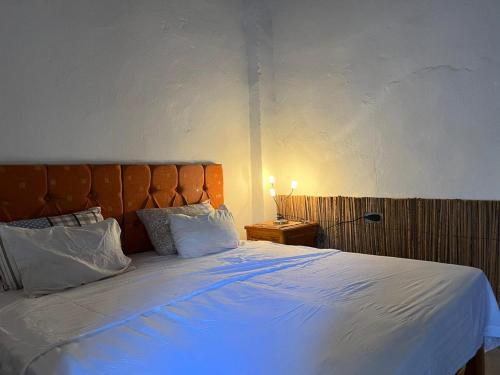 una camera da letto con un grande letto con lenzuola e cuscini bianchi di Maison d'hôtes "Dar Khalifa" a Tozeur