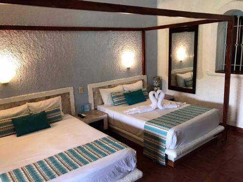 two beds in a hotel room with a mirror at Chez Waffle Hotel in Puerto Aventuras